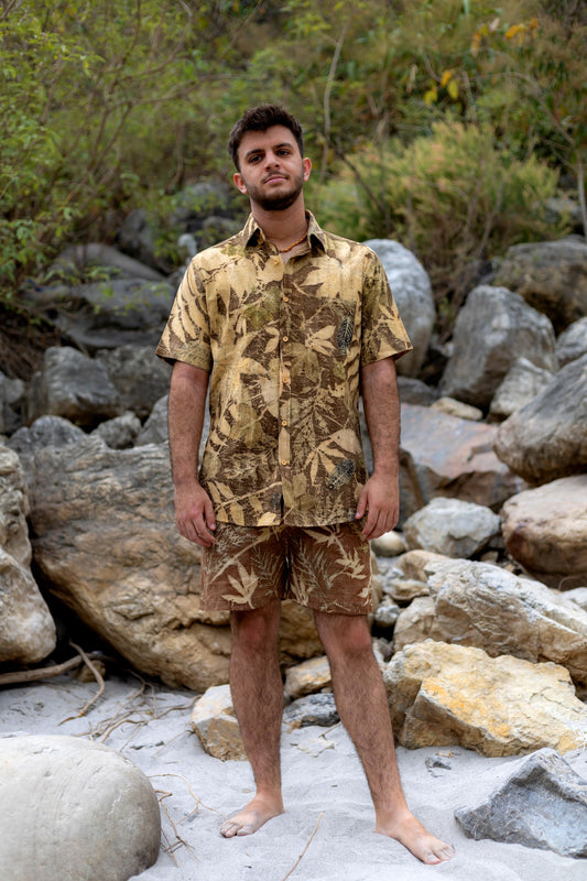 Man standing outdoors wearing a natural botanical eco-print short-sleeve shirt and matching shorts.