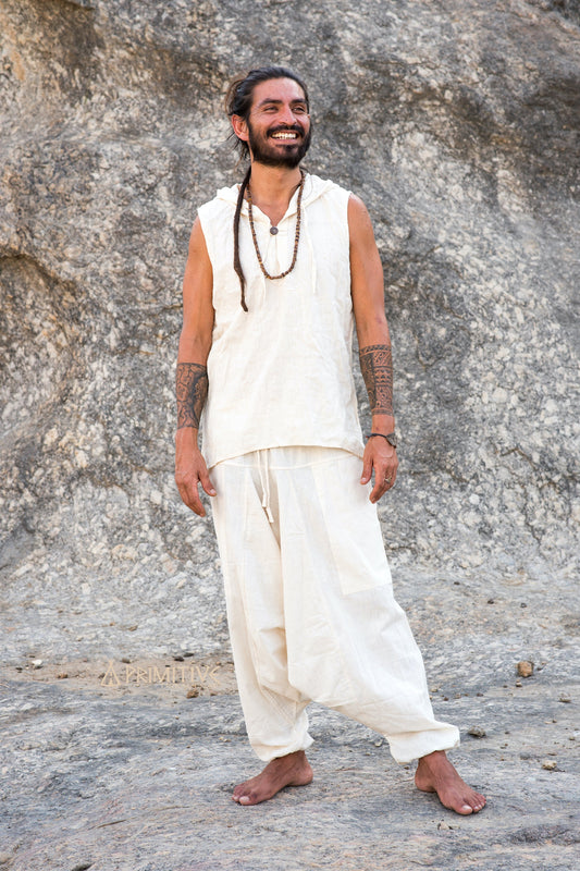 Full-body view of unisex natural cotton harem pants in neutral tone, showing relaxed drop-crotch silhouette and roomy fit, styled in a clean boho outfit outdoors.
