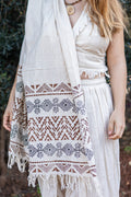 Woman wearing a patterned shawl over shoulders outdoors.
