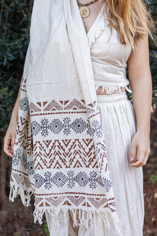 Woman wearing a patterned shawl over shoulders outdoors.