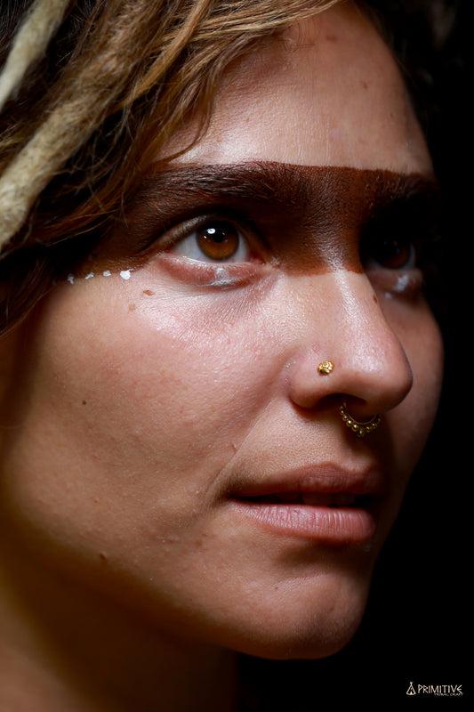 Close-up of a 9K gold tribal nose ring with spiral back