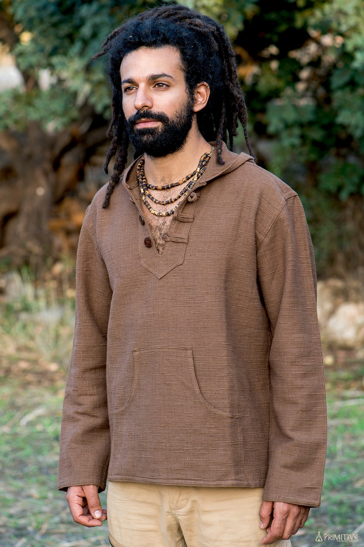 A man wearing a brown handwoven khadi cotton pullover with a hood and coconut buttons.