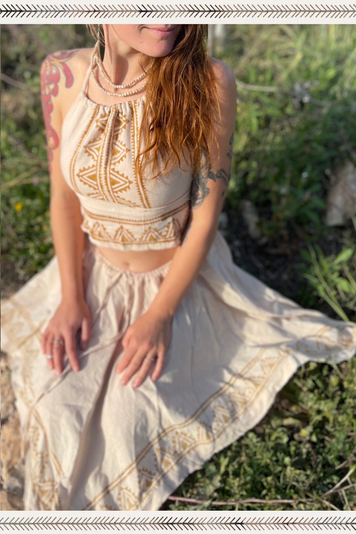 Woman wearing natural clothing featuring tribal-inspired camel blockprint top and skirt from Ancient Butterfly Outfit Skirt + Top Camel Blockprint set sitting outdoors on grass