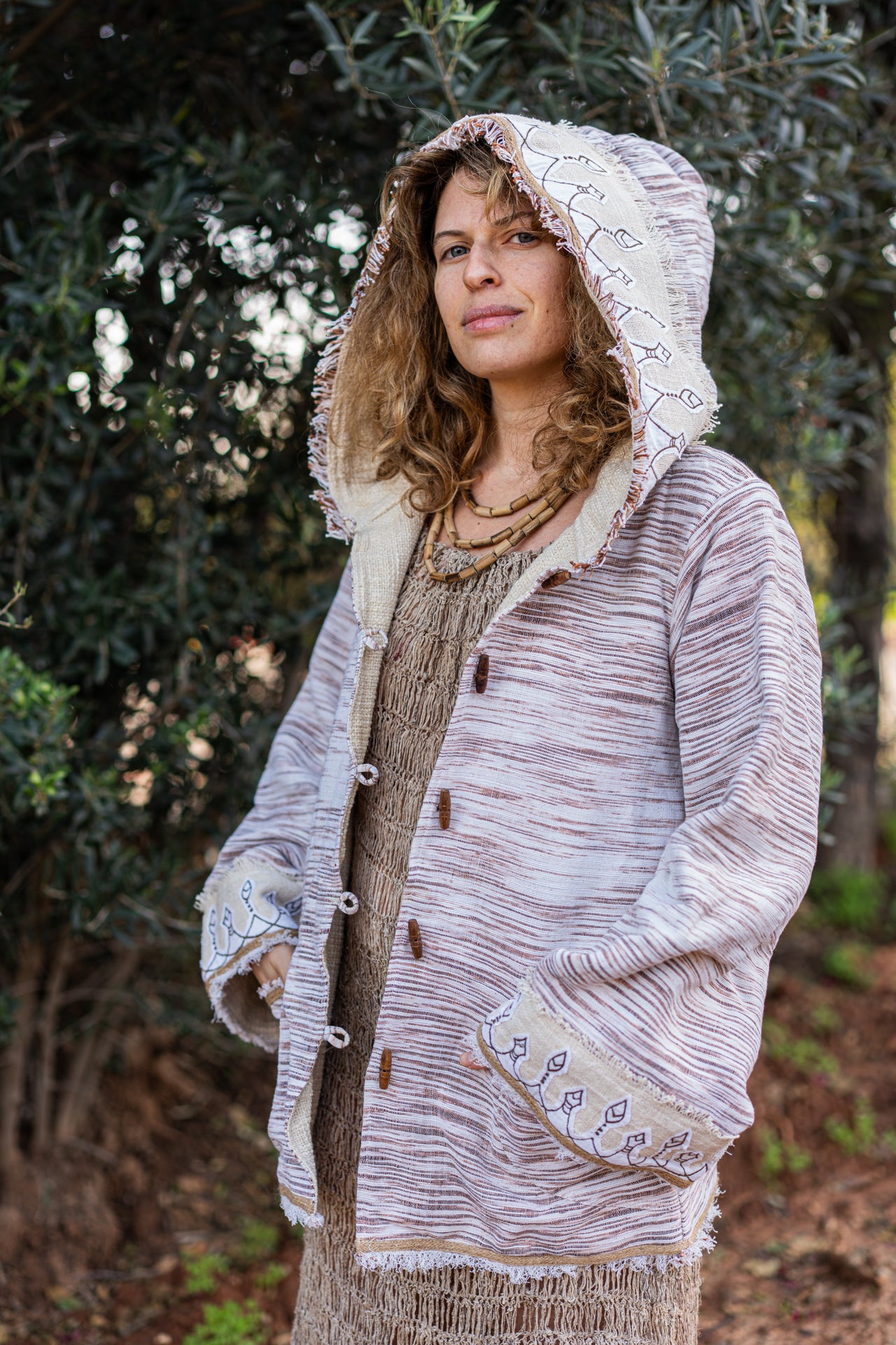 Bohemian textured cotton cardigan featuring rustic wooden toggle buttons and raw fringe edges on the hood