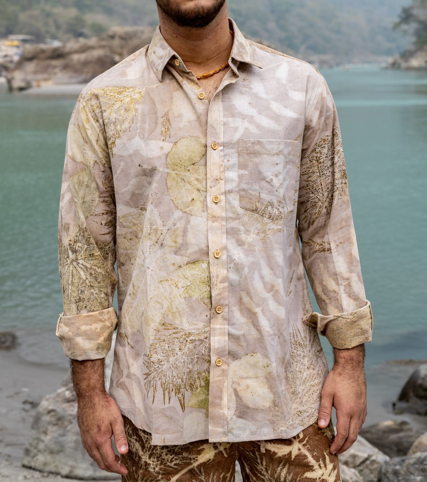Close up of a man wearing a light beige botanical dye long sleeves buttoned shirt. Eco-printed natural leaf fashion by Primitive Tribal Craft.