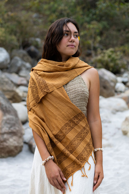 Woman outdoors wearing an earthy brown handwoven cotton scarf with tribal block print details. Bohemian slow fashion shawl