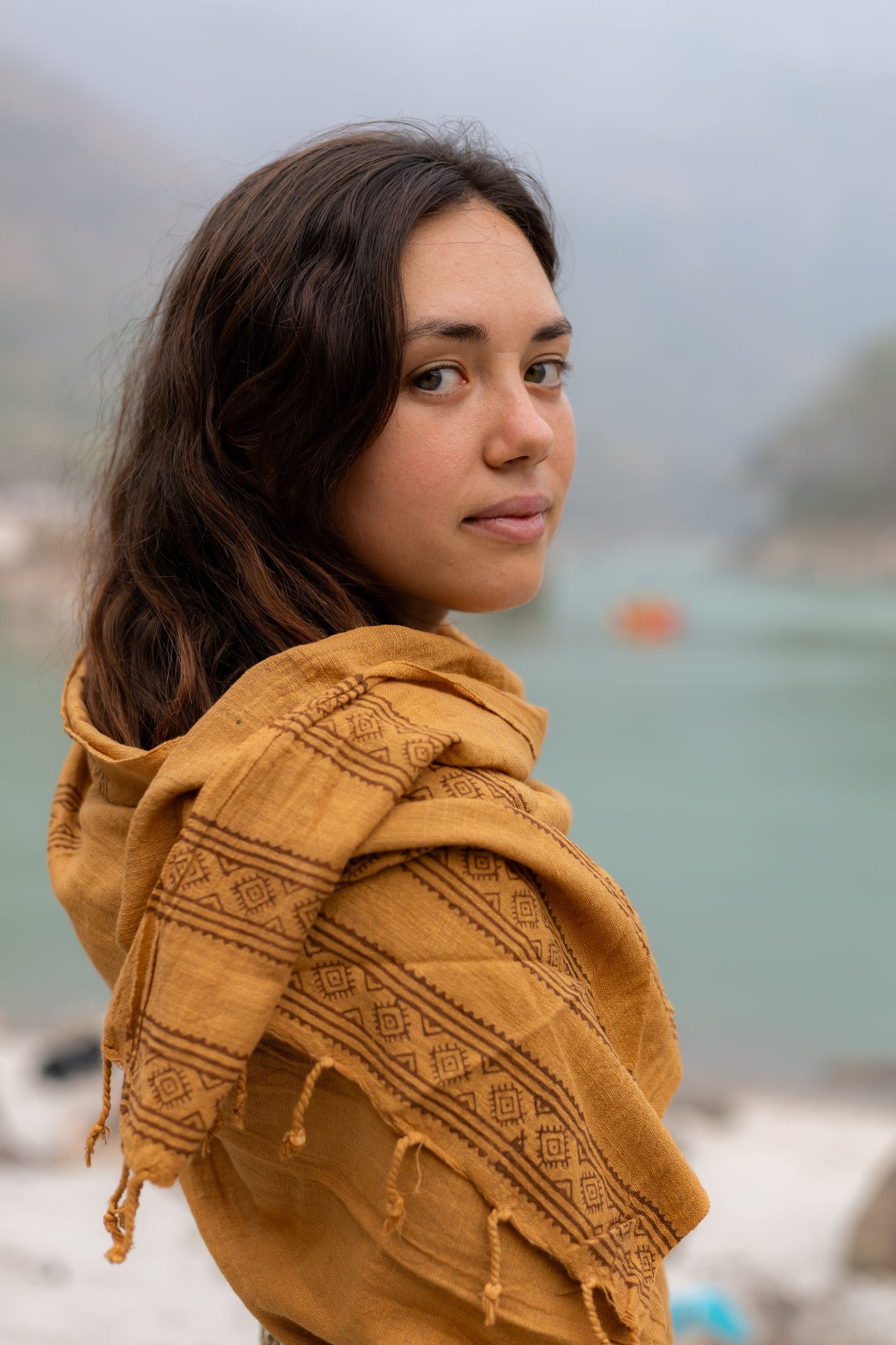 Close up of a brown block printed cotton scarf draped over a woman's shoulder. Handwoven tribal magic wrap with traditional wooden block patterns.