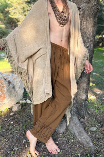 hippie man wearing brown cotton drawstring pants with tribal block prints, showcasing the loose straight-leg fit and natural fabric texture