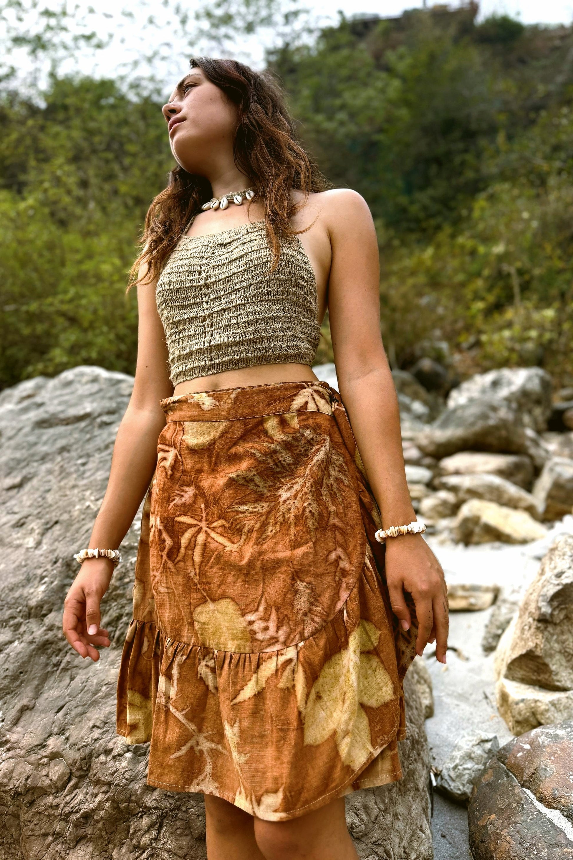 Front view of a woman modeling aan eco-printed brown wrap skirt featuring unique botanical leaf patterns.