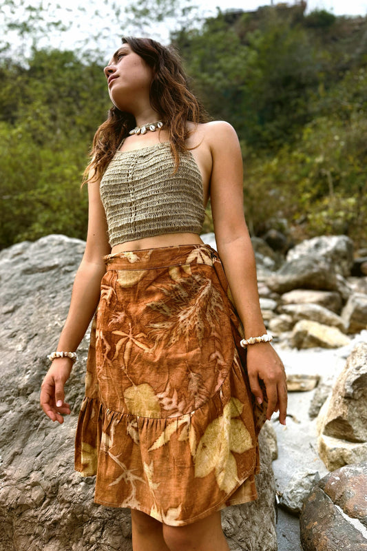 Front view of a woman modeling aan eco-printed brown wrap skirt featuring unique botanical leaf patterns.