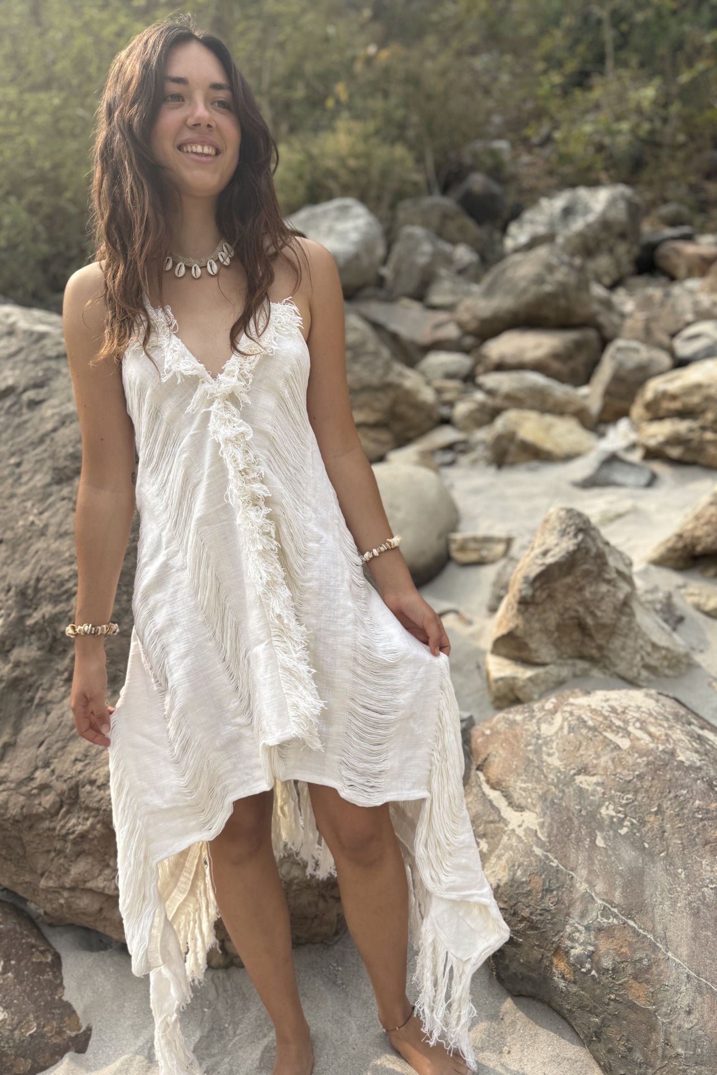 Woman in a white dress standing on a rocky beach
