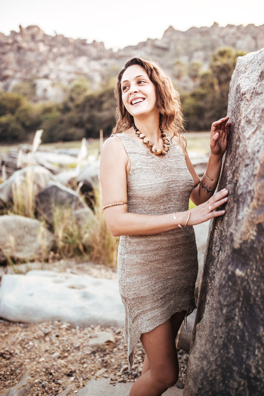 Woman in a Hand-knitted Himalayan nettle yarn dress standing next to a rock with a scenic background