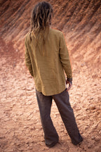 Back view of an camel handwoven linen shirt, showing its natural texture, relaxed fit and long cuffed sleeves.