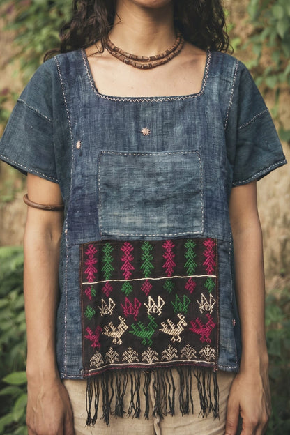 Women wearing a blue Hemp top with embroidered patterns and fringes against a natural background.