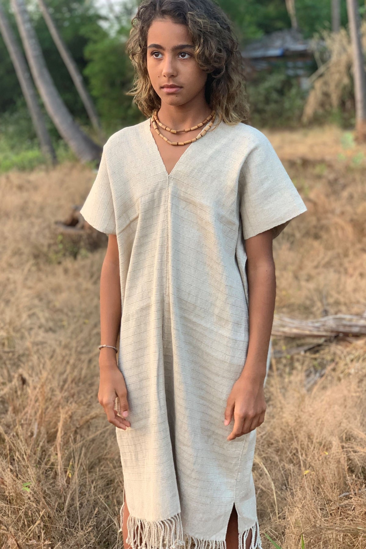 Young woman modeling the Karen Hill Tribe handwoven hemp kaftan in natural color, showing the V-neckline detail and relaxed short-sleeve fit.