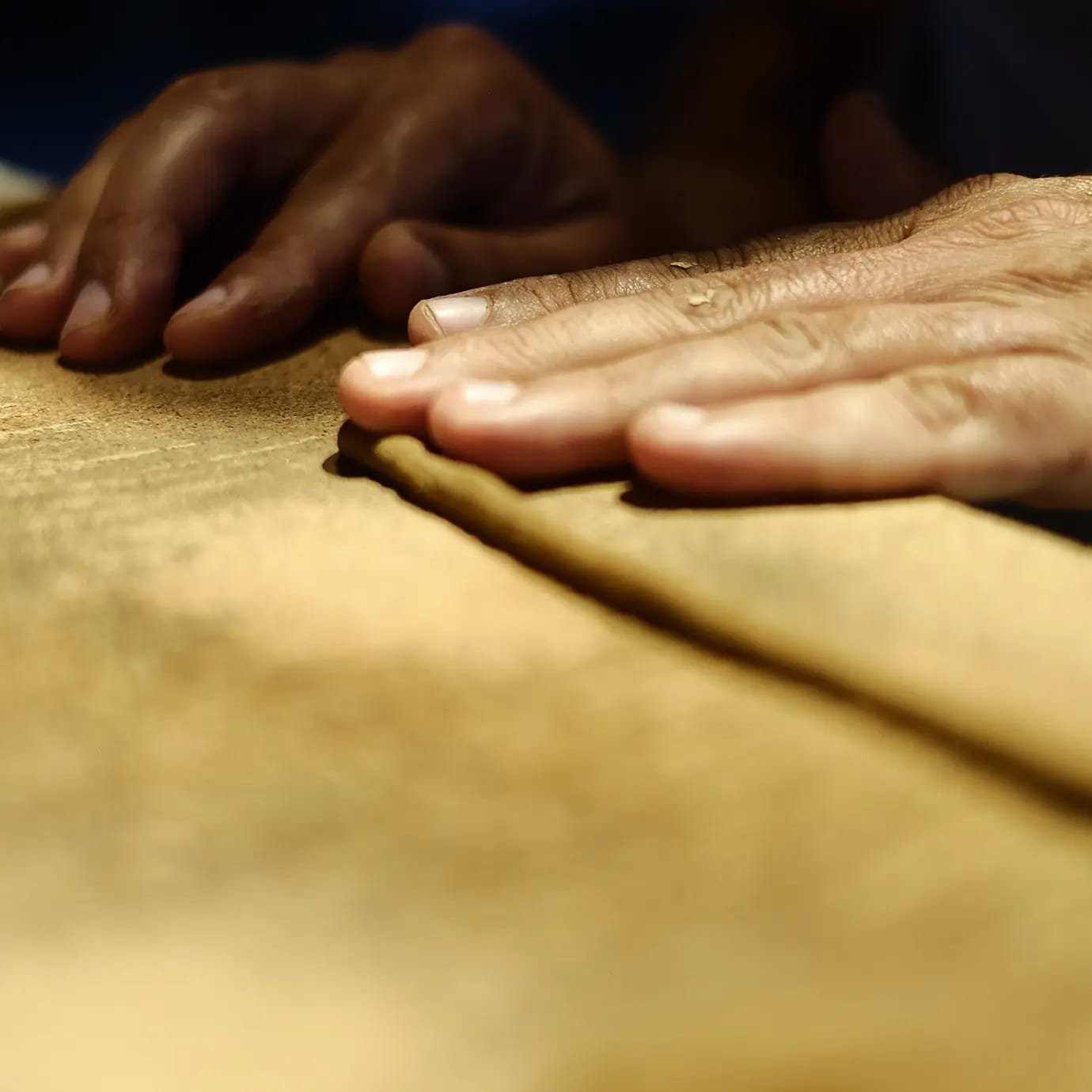 Close-up of hands hand-rolling natural incense sticks using pure resins and organic herbs on a wooden surface.