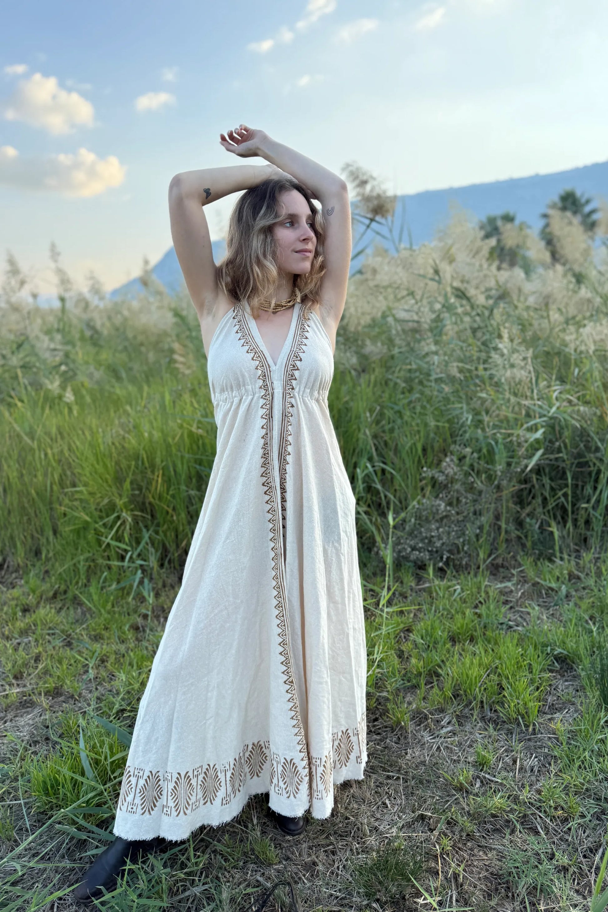 Woman wearing the Naya long butterfly dress, a natural cotton maxi dress with block print details and a deep V-neck, photographed outdoors.