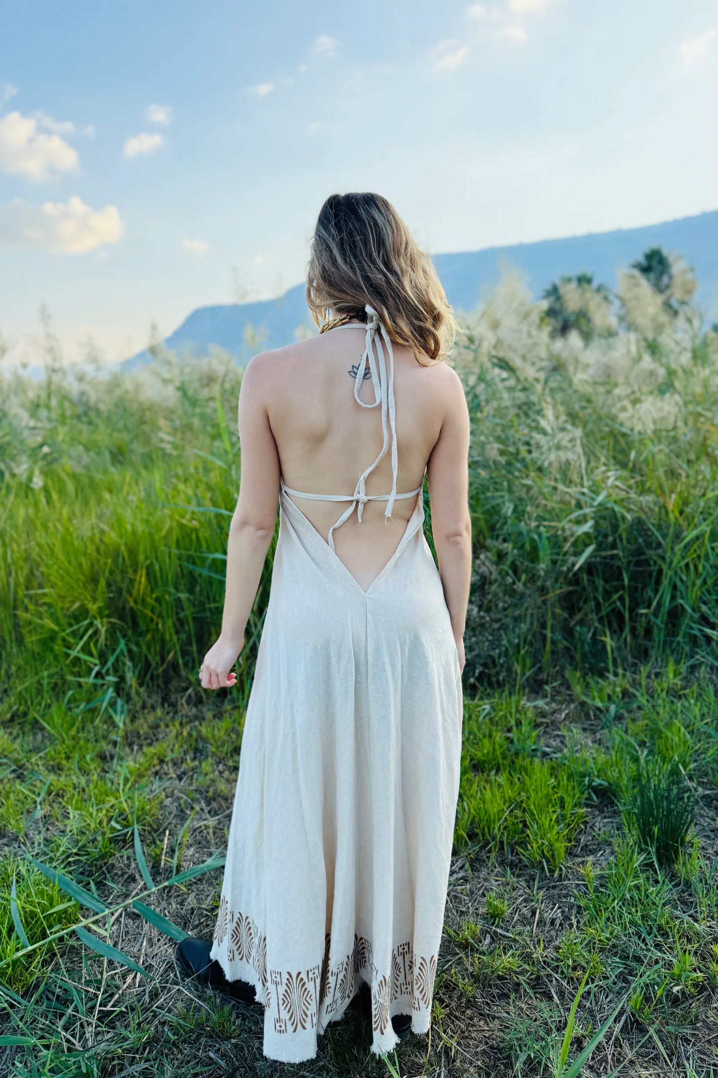 Back view of the Naya long butterfly dress, a flowy natural cotton maxi dress with block print details, worn outdoors.