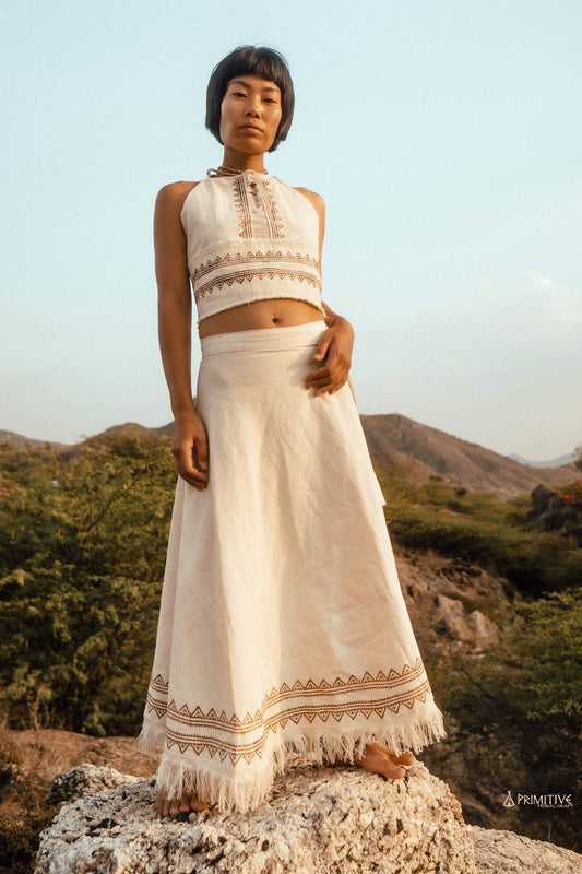 A woman wearing a lightweight white handwoven cotton top with subtle tribal block prints, standing in soft natural light