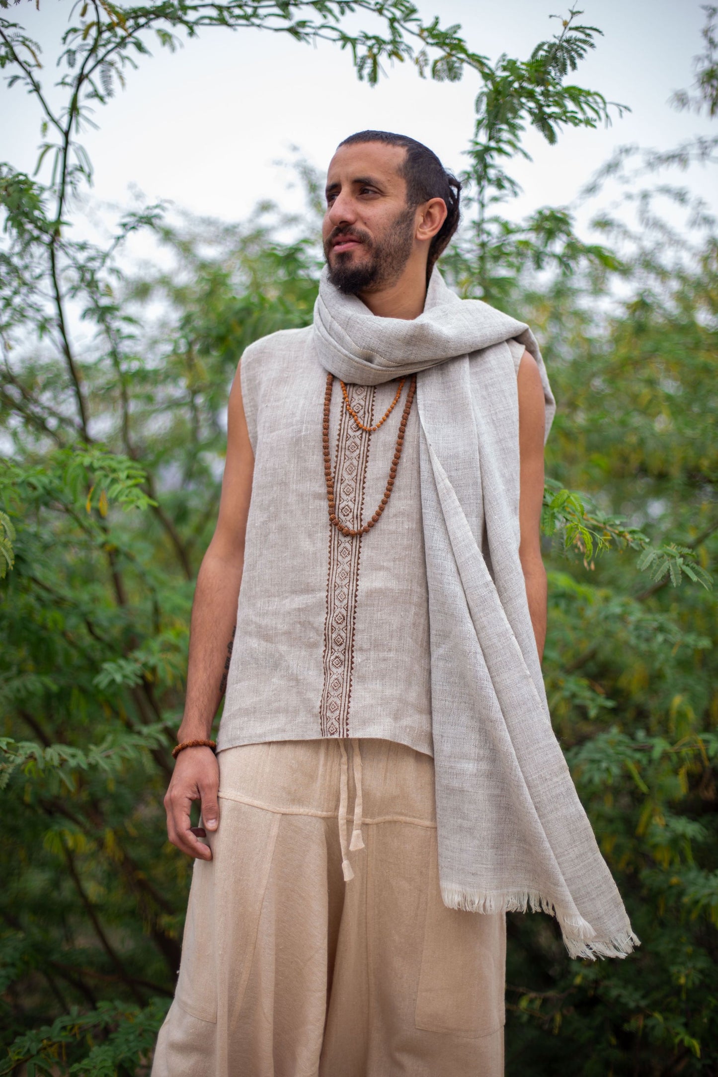 Man wearing a Grey Wool Shawl  outdoors with greenery in the background