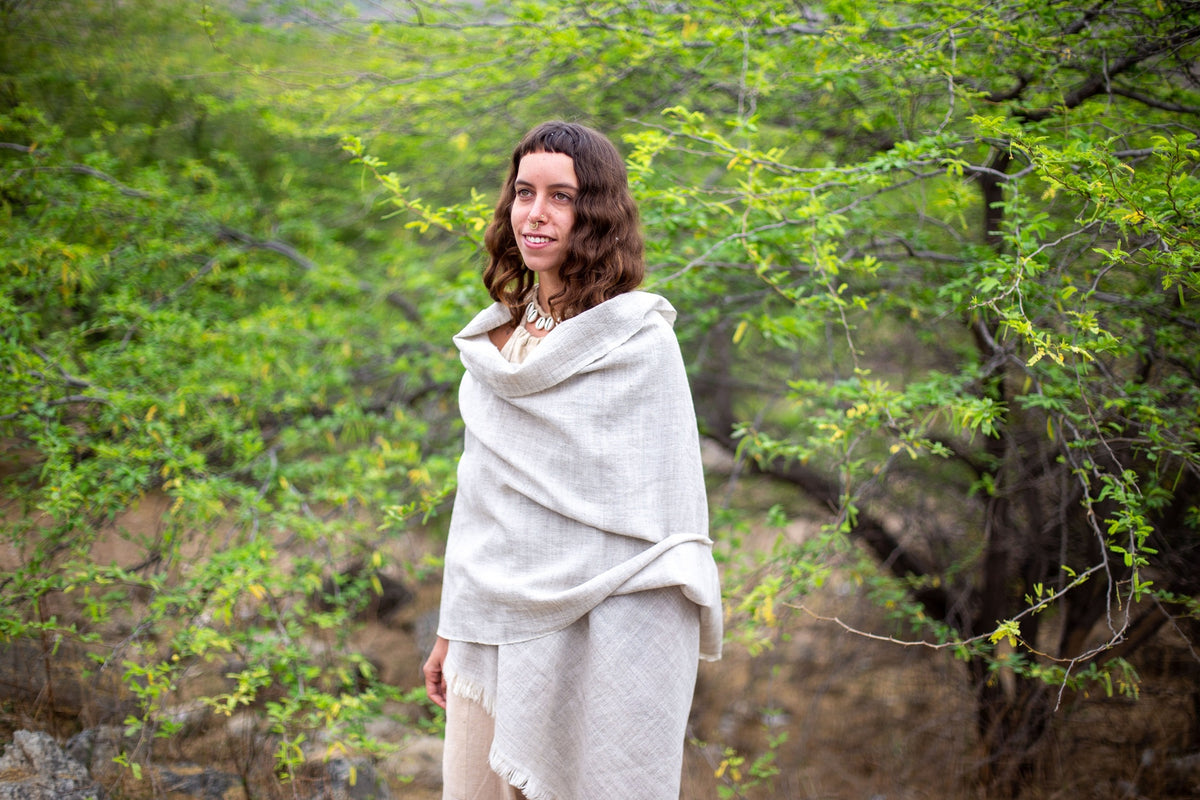 Woman wrapped in a Grey Wool Shawl standing in a natural setting with greenery.