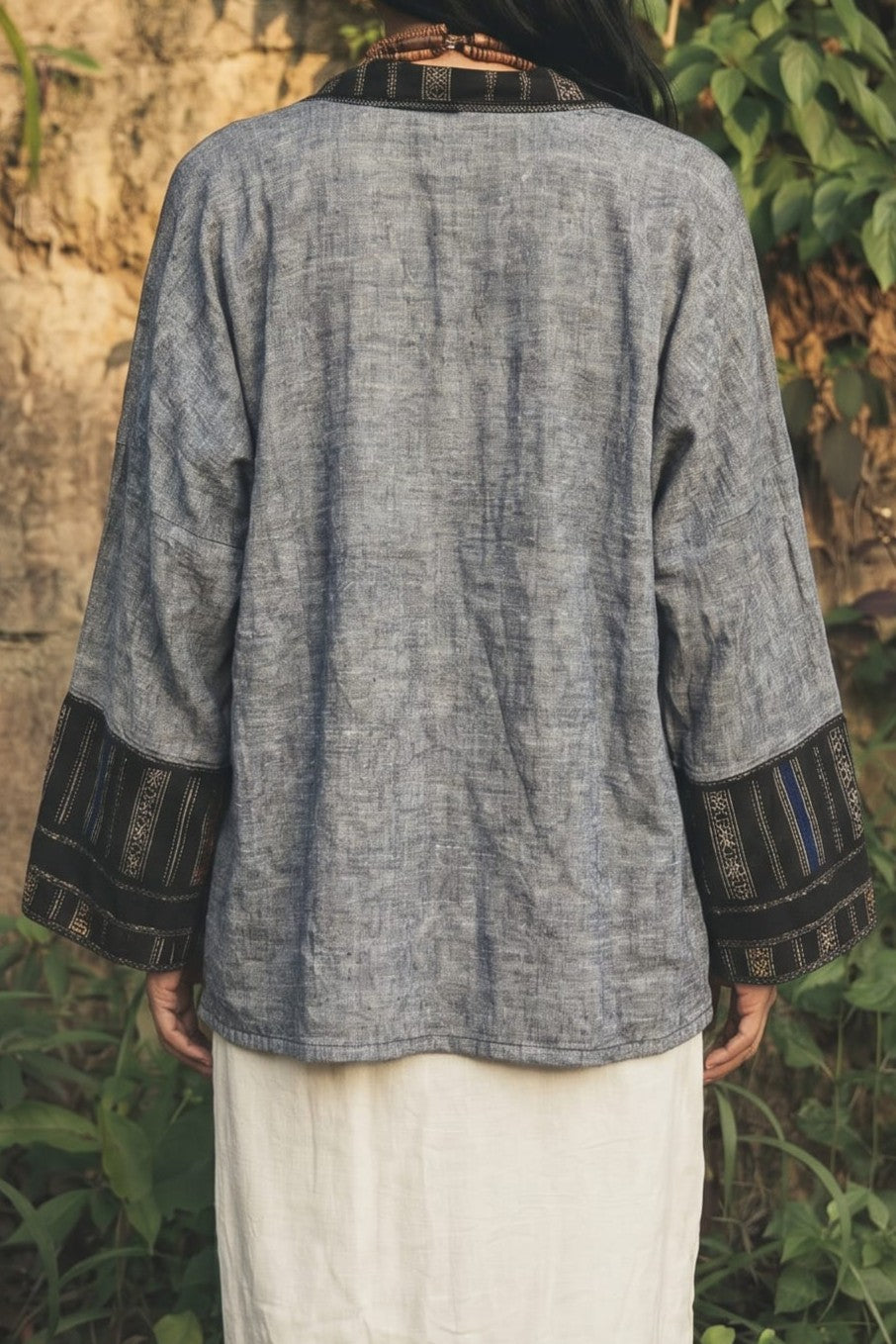Person wearing a gray textured jacket with black trim in a natural setting
