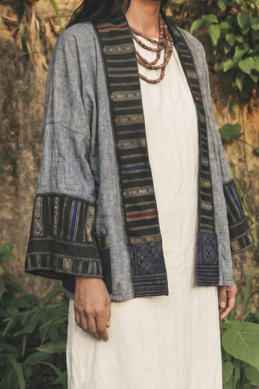 Person wearing a traditional patterned cardigan over a white outfit with a natural background