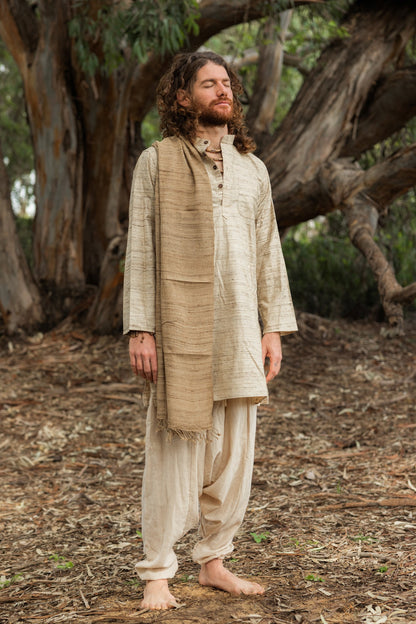 Man with eyes closed wearing a full-length natural wild silk kurta, standing peacefully in front of a large tree