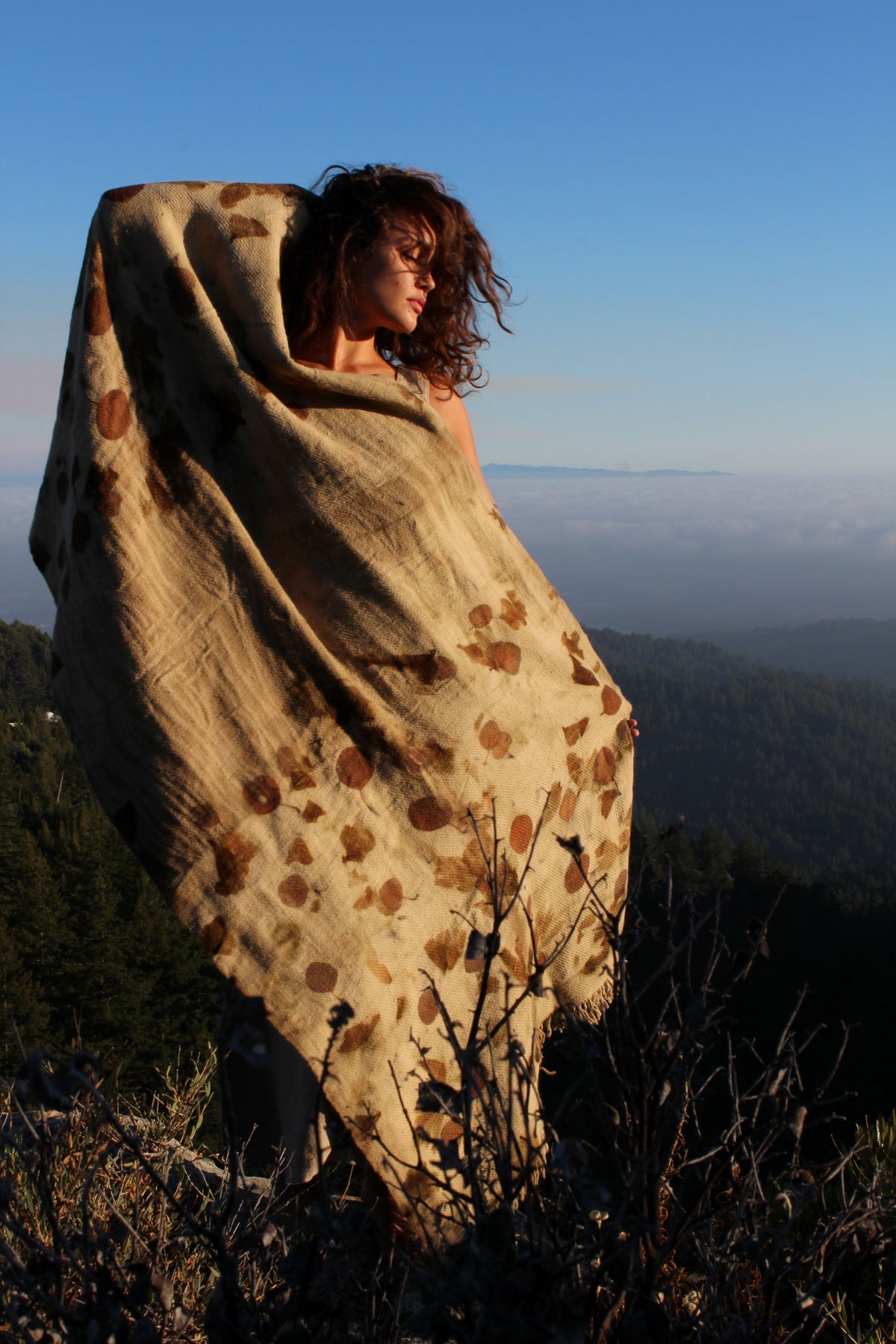 Ancient Path pure wool botanical print shawl wrapped around a woman outdoors, featuring natural leaf and plant patterns in earthy brown tones.