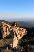 Woman wearing the Ancient Path handwoven pure wool shawl with botanical eco print, standing on a mountain overlooking a forest landscape.