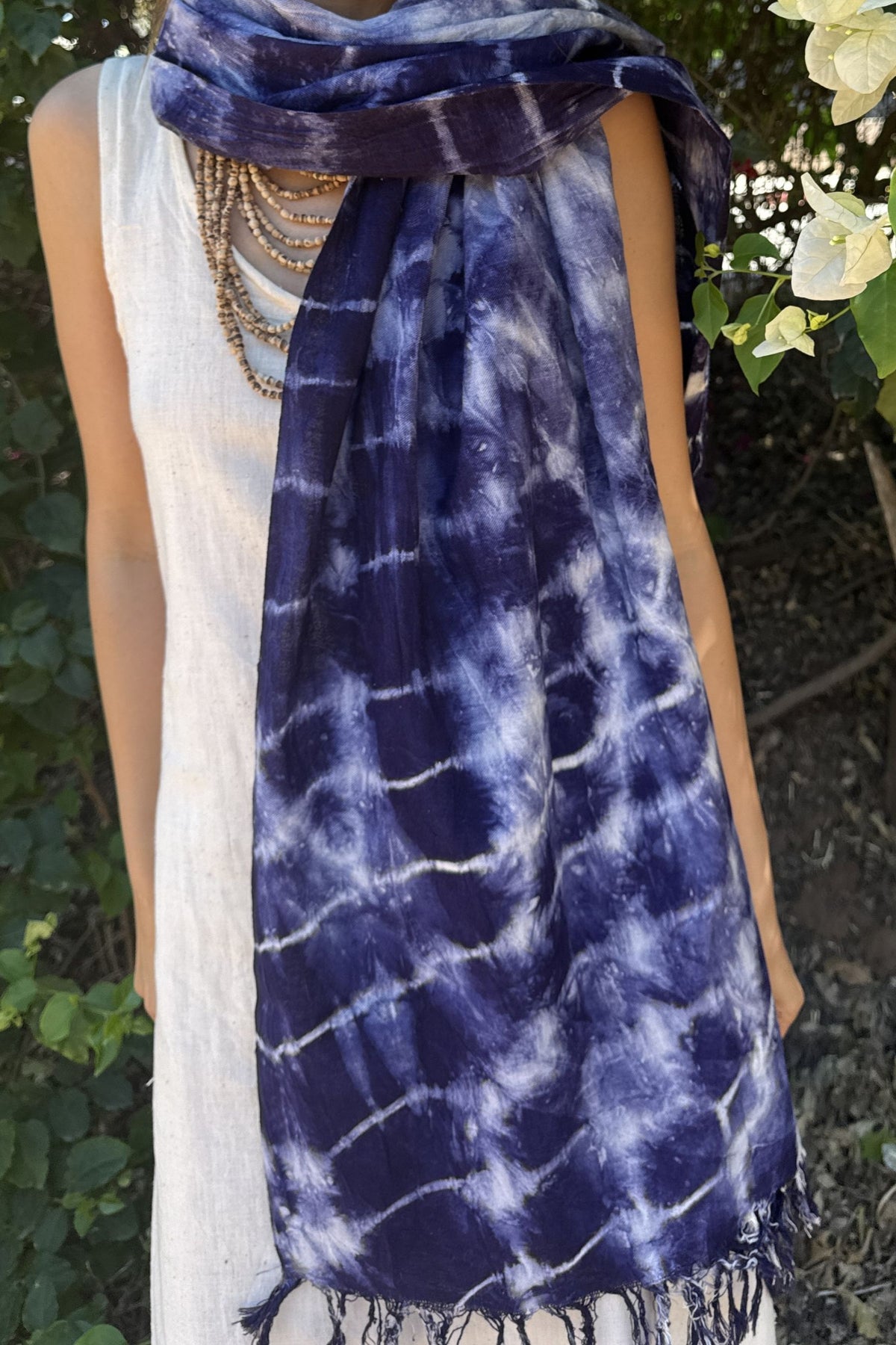 Person wearing an indigo tie-dye Shawl with a white sleeveless top, standing outdoors.
