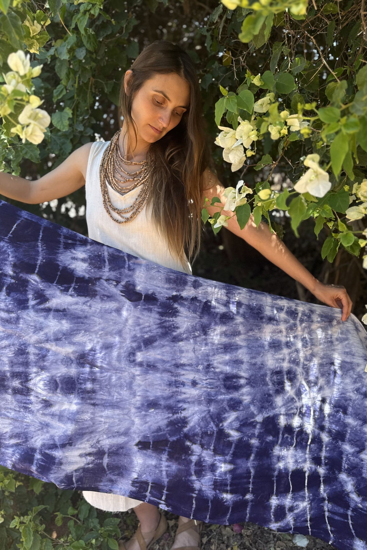 Woman holding a large piece of tie-dye cotton fabric in a garden setting