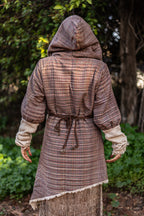 Back view of an asymmetric wrap jacket showing the pointed hemline, deep hood, and adjustable waist tie.