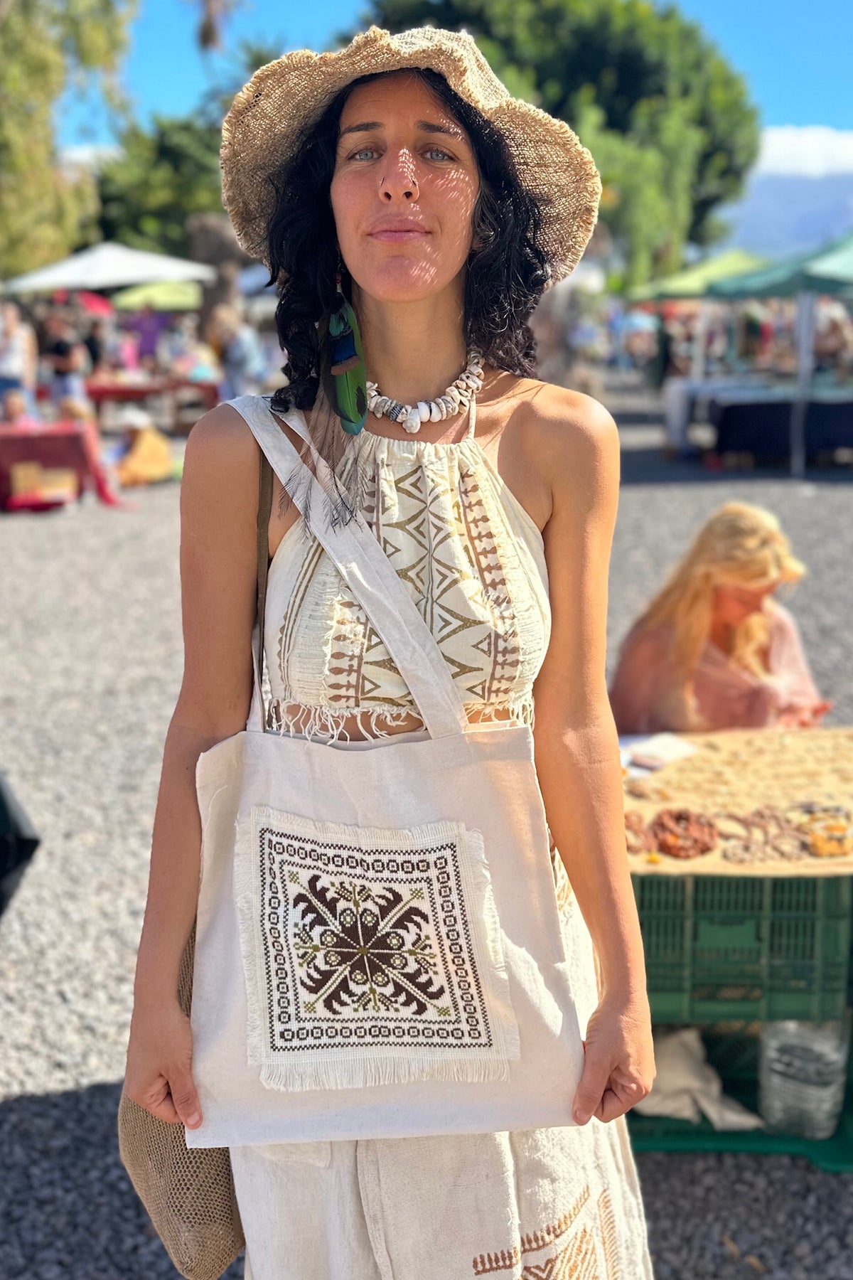 A person holding a beige shopping bag with Palestinian hand embroidery patch.