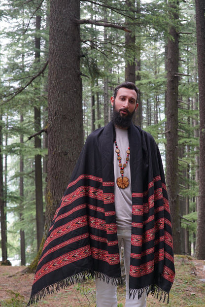 Man wearing a black handloom Kullu wool shawl with red tribal stripes in a forest