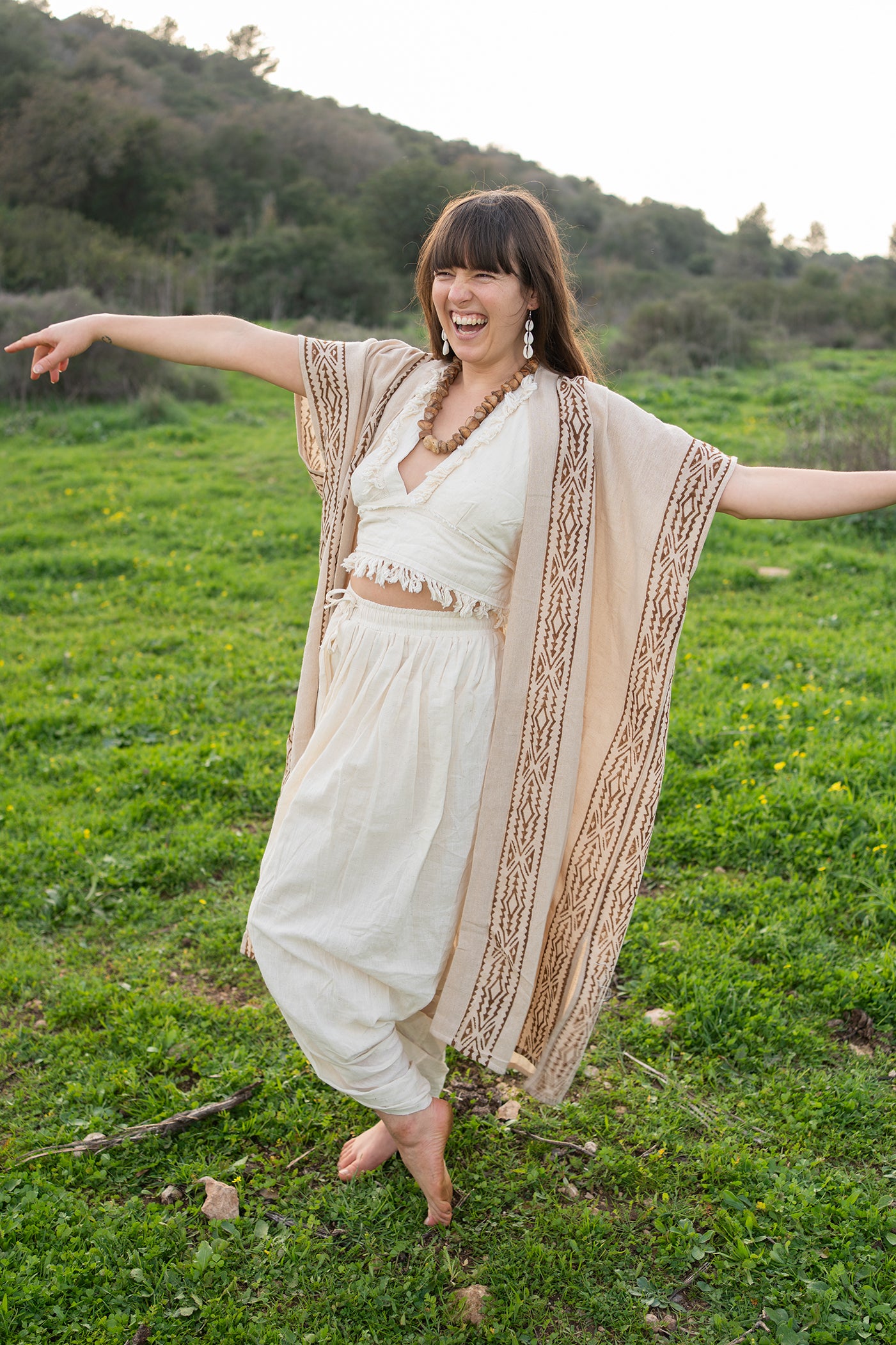 Women showing the flow and drape of a lightweight cotton kimono with hand block prints, arms open in a joyful movement pose outdoors.