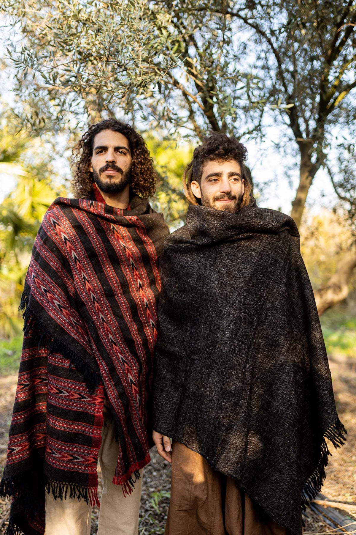 Two men wearing handloom yak wool shawls outdoors, one black and one tribal pattern.
