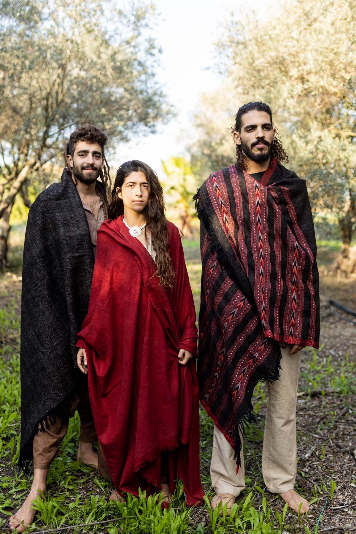 Group wearing handwoven yak wool shawls and wraps in nature, including a brown tribal patterned shawl.