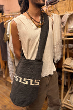 Man wearing a dark handmade wool arhuaca bag featuring a single white geometric tribal pattern at the bottom