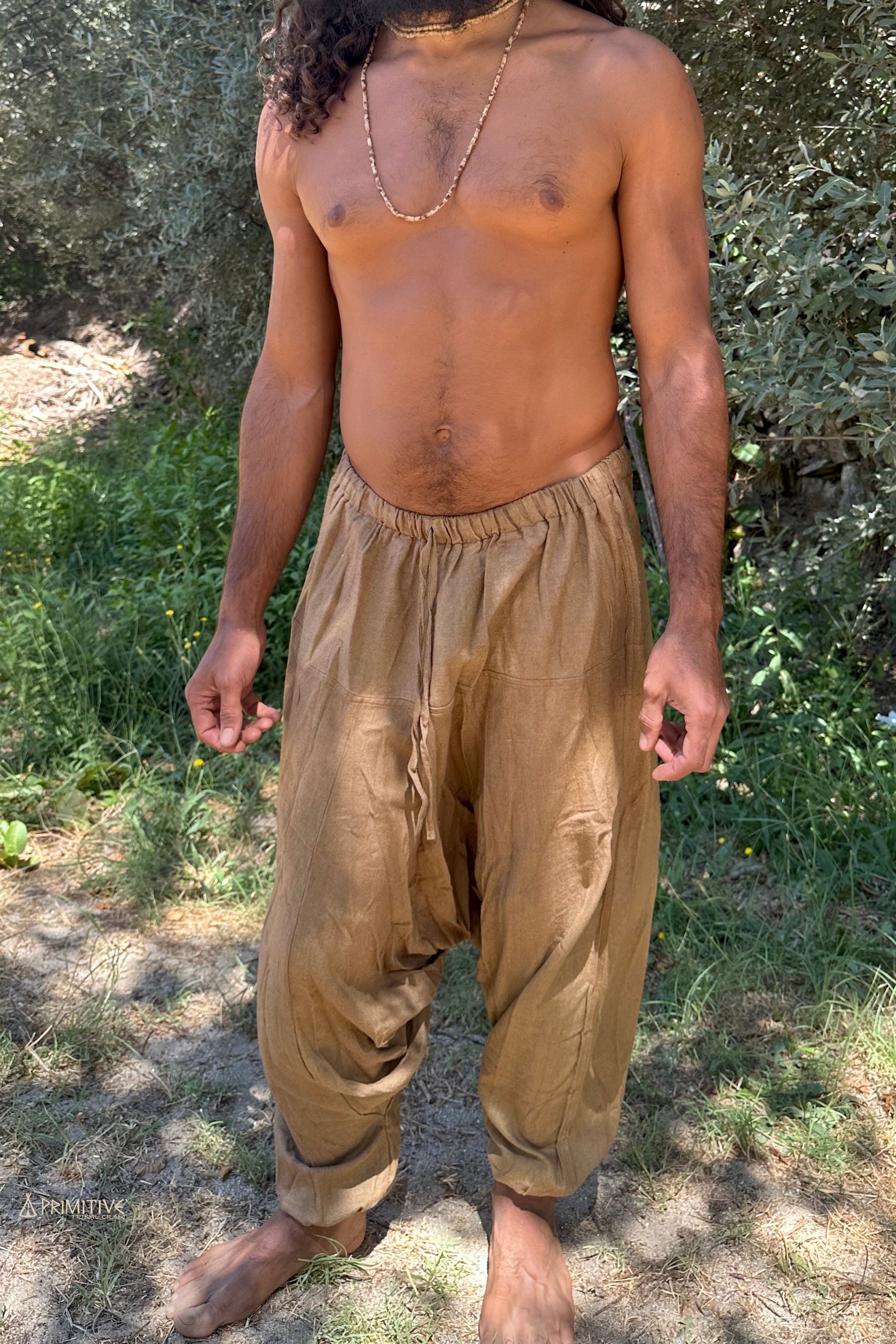 Handwoven raw silk harem pants in earthy brown on a man, relaxed drop-crotch silhouette with elastic waist for free movement and comfort.