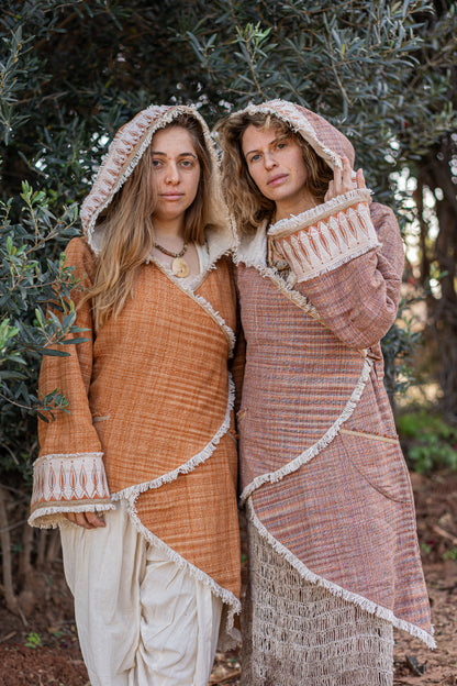 Two women wearing earth-tone hooded Khadi cotton jackets with rustic fringe and tribal embroidery details in a natural setting