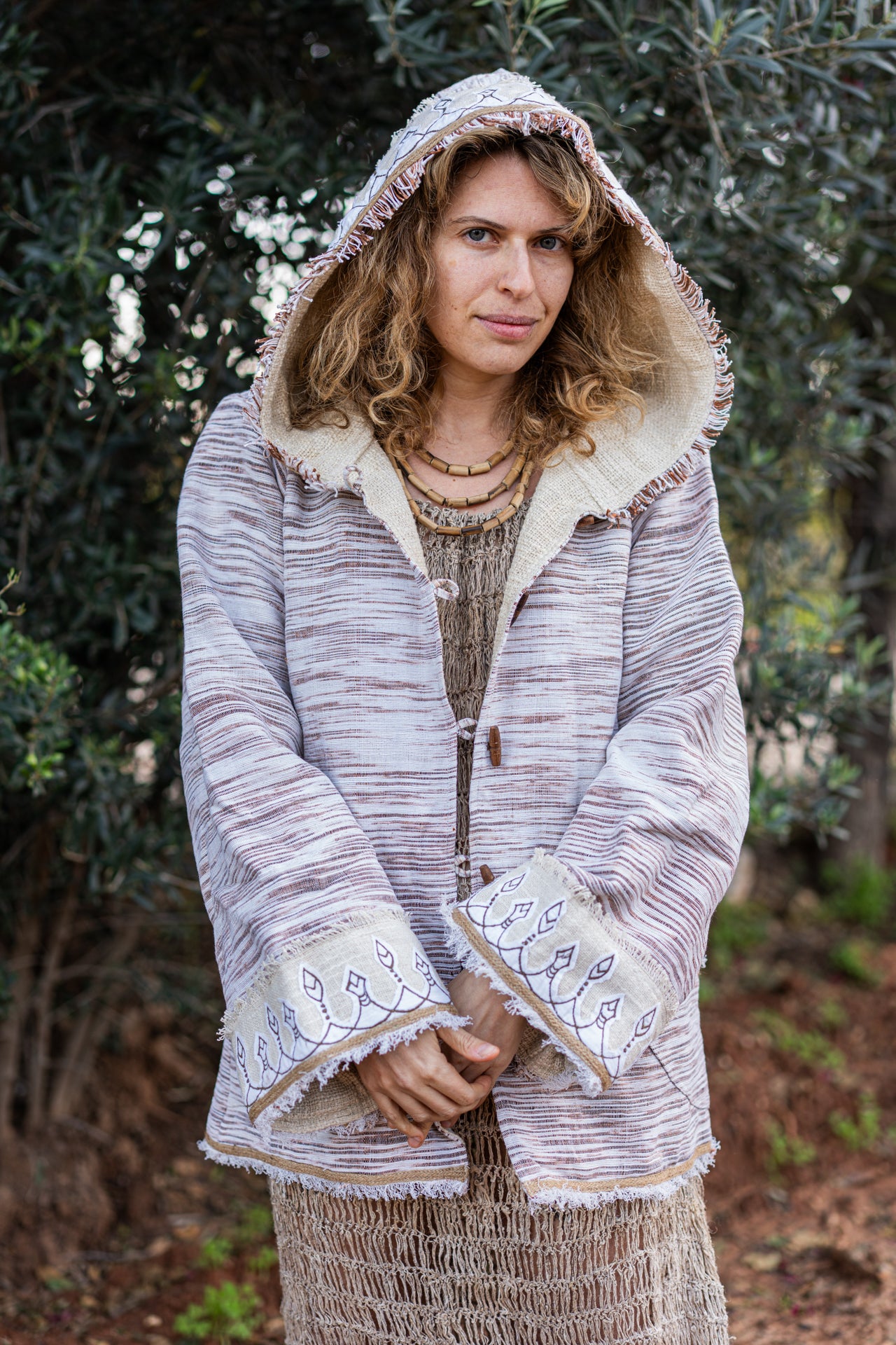Woman wearing a light-colored hooded Khadi jacket with hand-drawn embroidery on the cuffs