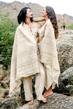 a couple standing covered in a large wild silk shawl