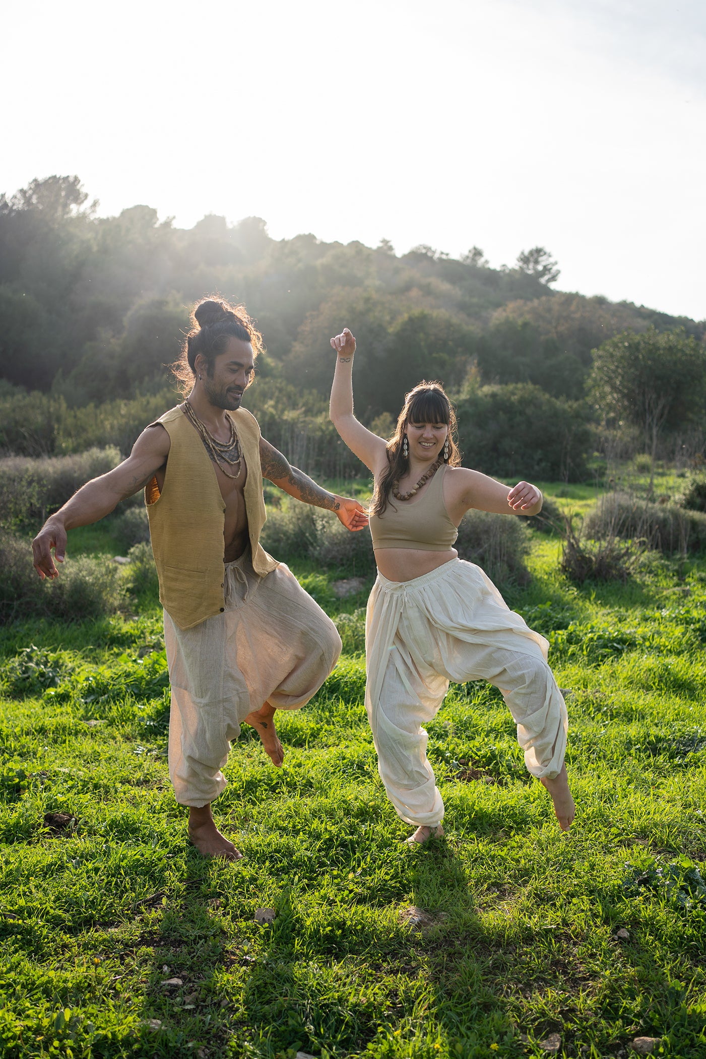 Two people dancing outdoors; man wears camel khadi cotton vest and natural pants, styled for earthy boho festival wear.
