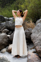 Woman standing among rocks wearing a beautiful white handloom khadi cotton long wrap skirt. Sustainable bohemian clothing for women.