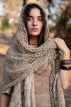 Close-up portrait of a woman wearing a 100% Wild Himalayan Nettle shawl, showing the intricate open-knit texture and natural beige fiber.