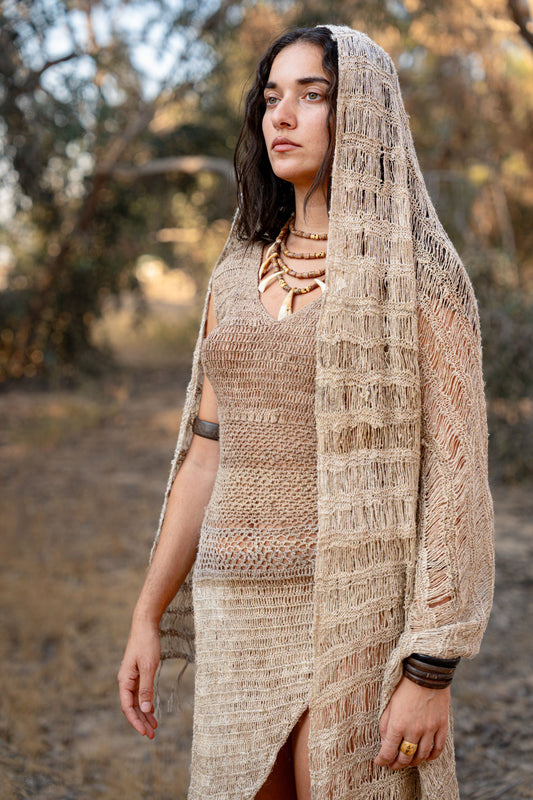 Model wearing a lightweight natural nettle-fiber shawl with an open-weave texture, draped over her head outdoors