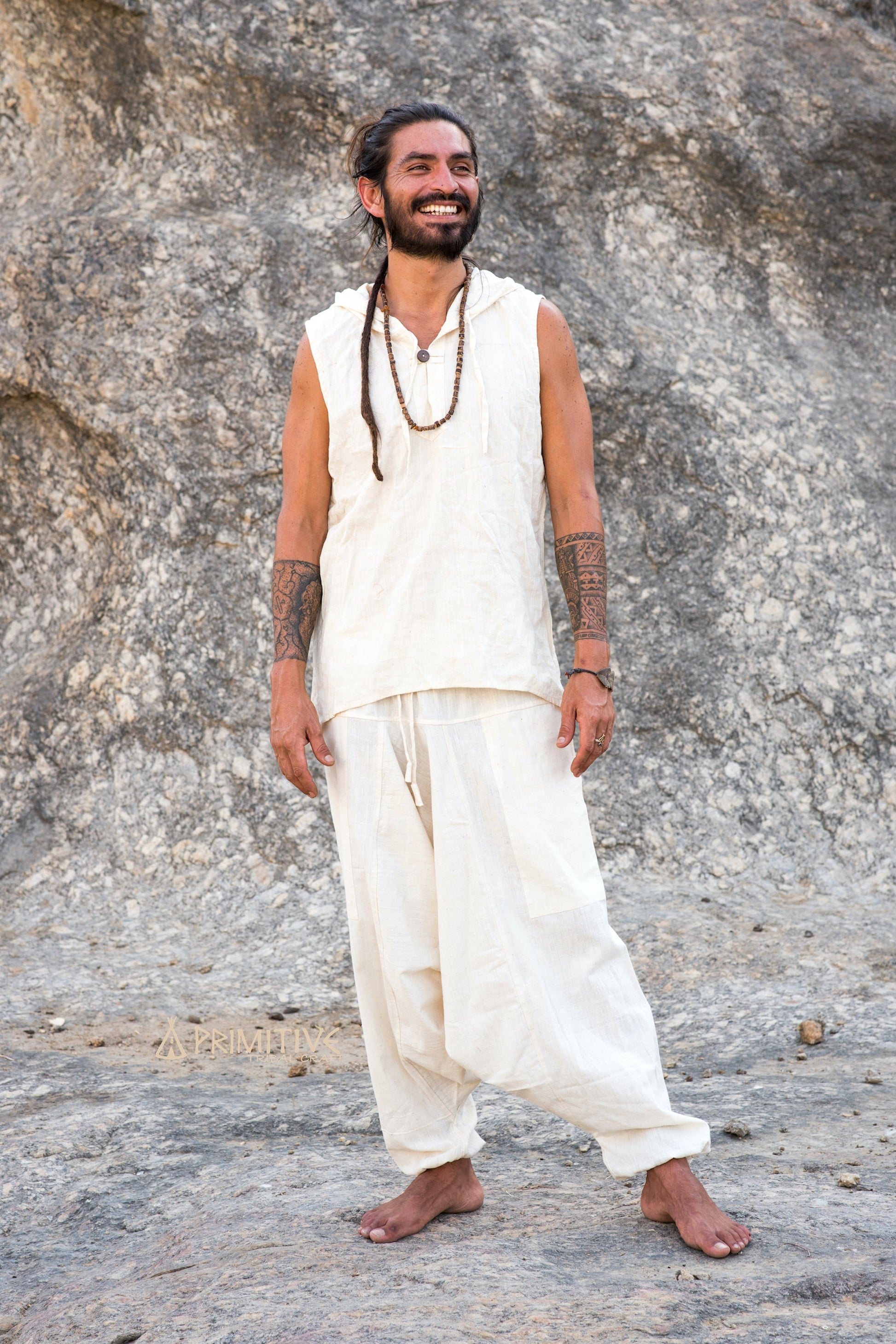 Full-body view of unisex natural cotton harem pants in neutral tone, showing relaxed drop-crotch silhouette and roomy fit, styled in a clean boho outfit outdoors.