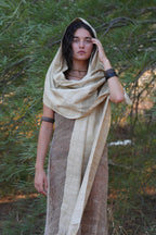 Full-body view of a model wearing a handwoven mulberry raw silk shawl as a hood and wrap, styled in a natural outdoor setting.