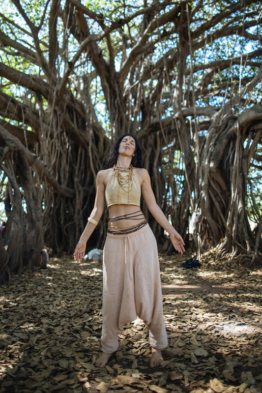 Women wearing beige natural cotton harem pants, loose drop crotch fit with drawstring waist, boho yoga look outdoors